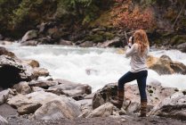 Rear view of woman photographing a flowing stream — Stock Photo