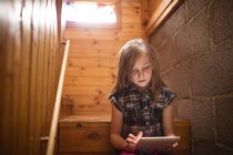 Kleines Mädchen mit Tablet auf der Treppe zu Hause — Stockfoto