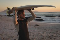 Surfer trägt Surfbrett am Strand am Kopf — Stockfoto