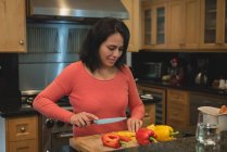 Femme coupant des légumes dans la cuisine à la maison — Photo de stock