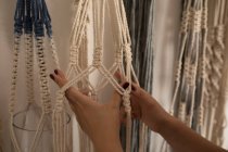 Cropped image of woman knotting strings in workshop — Stock Photo