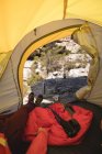 Escursionista sdraiato in tenda con attrezzatura da campeggio in una giornata di sole — Foto stock