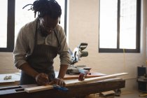 Carpinteiro medindo prancha de madeira com escala em oficina — Fotografia de Stock