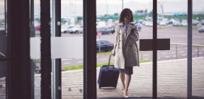 Вишукана бізнес-леді, що використовує мобільний телефон, прибуваючи в готель — стокове фото