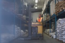 Uomo che solleva sacco di cereali con carrello elevatore in fabbrica — Foto stock
