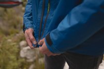 Close-up of hiker hand pulling zipper of waterproof rain jacket — Stock Photo