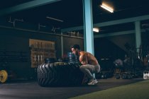 М'язистий чоловік займається з важкою шиною в фітнес-студії — стокове фото