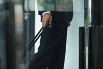 Cropped image of businessman with trolley bag leaving hotel — Stock Photo