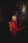 Hiker wearing head torch, inspecting rocks in a dark cave — Stock Photo