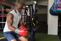 Homme âgé réfléchi appuyé contre le ring de boxe dans la salle de gym . — Photo de stock