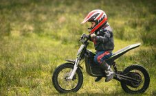 Side view of kid rider riding a bike in garden — Stock Photo