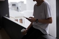 Молодий чоловік використовує мобільний на балконі — стокове фото