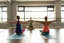 Trainer assisting women in practicing yoga at fitness studio. — Stock Photo