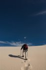 Rückansicht des Wanderers mit Wanderstock, der auf Sand geht — Stockfoto