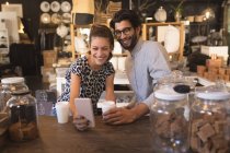 Пара, делающая селфи с мобильным телефоном у стойки в кафе — стоковое фото