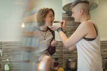 Lesbianas pareja comida degustación en cocina en casa . - foto de stock