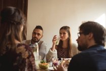 Friends interacting while having meal at table — Stock Photo
