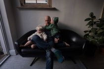 Батько грає з дітьми у вітальні вдома на дивані . — стокове фото