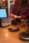 Клієнт здійснює оплату за допомогою смарт-годинника за лічильником у кафе — стокове фото