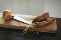 Primo piano di coltello, carota e cipolla sul tagliere — Foto stock