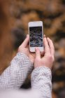 Крупный план женщины, смотрящей на осеннюю фотографию в мобильном телефоне — стоковое фото