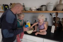 Vater mit Kindern bereitet zu Hause in der Küche Essen zu. — Stockfoto