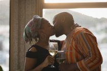Couple embrasser tout en ayant du vin par la fenêtre à la maison . — Photo de stock