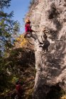 Mulher alpinista lutando até a montanha rochosa em um dia ensolarado — Fotografia de Stock