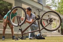 Père et fils interagissent les uns avec les autres pendant la réparation du cycle dans le jardin — Photo de stock