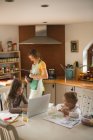 Дівчина з сім'єю використовує ноутбук на кухні вдома — стокове фото