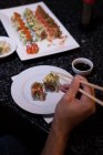Un homme ramasse des sushis avec des baguettes dans un restaurant — Photo de stock