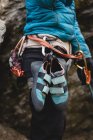 Mid section of climber standing with climbing shoes attached to harness — Stock Photo