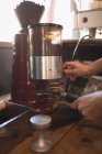 Barista moagem de grãos de café em uma cafeteria — Fotografia de Stock