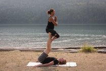 Vista lateral de mujeres deportistas practicando acro yoga en un terreno abierto - foto de stock
