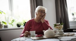 Nachdenkliche Seniorin denkt im heimischen Wohnzimmer nach — Stockfoto