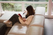 Woman reading a book in living room at home — Stock Photo