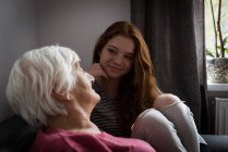 Enkelin interagiert mit Großmutter im heimischen Wohnzimmer — Stockfoto