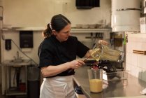Koch entleert eine gemahlene Paste in einem Container in der Großküche — Stockfoto