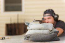 Mann zielt an sonnigem Tag mit Scharfschützengewehr auf Scheibe im Schießstand — Stockfoto