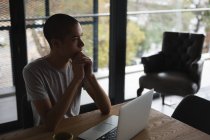 Nachdenklicher junger Mann benutzt Laptop zu Hause — Stockfoto