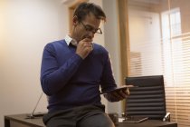 Homme d'affaires utilisant la tablette numérique tout en étant assis au bureau . — Photo de stock