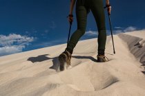Unterteil einer Wanderin mit Trekkingstock, die auf Sand geht — Stockfoto