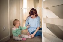 Mãe ajudando sua menina no uso de sapatos em casa — Fotografia de Stock