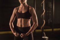 Parte média da mulher mostrando seu músculo no ginásio — Fotografia de Stock