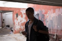 Молодой человек использует мобильный телефон в здании — стоковое фото