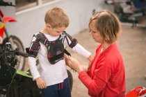 Mother preparing her son for bike riding in garage — Stock Photo