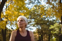 Thoughtful senior woman in a park on a sunny day — Stock Photo
