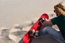 Homme portant un panneau de sable dans une dune de sable par une journée ensoleillée — Photo de stock