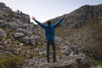 Vista posteriore dell'escursionista in piedi sulla roccia con le mani sollevate — Foto stock