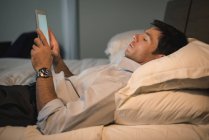 Uomo d'affari che utilizza tablet digitale in camera da letto in hotel — Foto stock